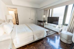 a white bedroom with a large bed and a flat screen tv at the best charming condo on the Nile in Cairo