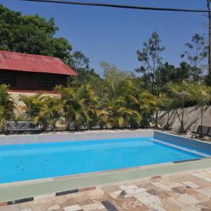 una piscina frente a una casa con palmeras en Rancho paola nature, en Cotuí