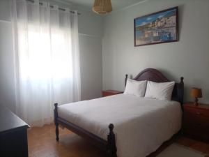 - une chambre avec un lit et une fenêtre avec des rideaux blancs dans l'établissement AL Bela Vida, à Tavira