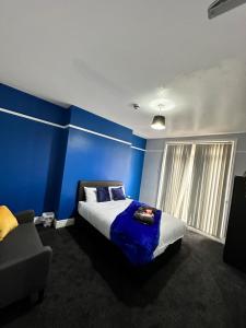 um quarto com paredes azuis, uma cama e um sofá em Quirky Oasis Queens em Liverpool