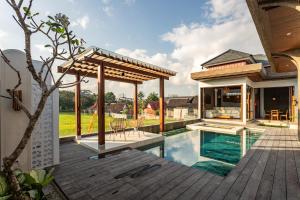 um deque exterior com uma piscina e uma casa em Bellini Villa Canggu em Canggu