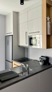a white kitchen with a sink and a microwave at LAWENDOWE NOCOWANIE Zdrojowa 9 lokal 1B in Kudowa-Zdrój +13 photos