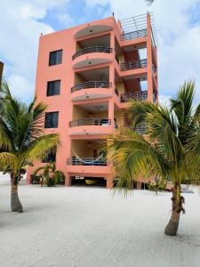 a pink building with palm trees in front of it at Bay Towers in Caye Caulker