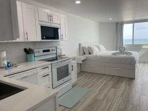 a kitchen with white cabinets and a bed in a room at Top of the Gulf 815 in Panama City Beach