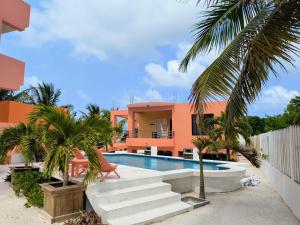 a villa with a swimming pool in front of a house at Bay Towers in Caye Caulker