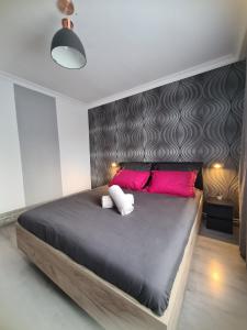 um quarto com uma grande cama preta e almofadas cor-de-rosa em Cosy escape em Sfântu Gheorghe