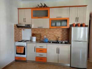 a kitchen with orange and white cabinets and a refrigerator at Apartment in Lungo Mare Vlore in Vlorë