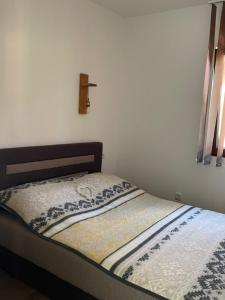 uma pequena cama num quarto com uma cruz na parede em Drinsko Srce em Ljubovija
