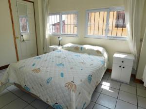a bedroom with a bed and two windows at Casa Xelaju Apartments in Quetzaltenango