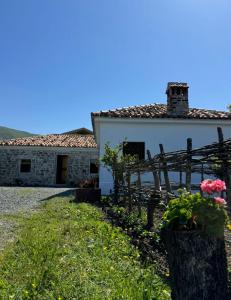 a house with a fence and flowers in front of it at Guesthouse Vitoria - Mrizi i Zanave in Fishtë