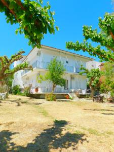 a large white building with trees in the foreground at Κωνσταντίνος Έλενα Studios in Pefki