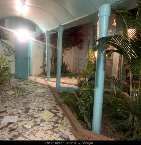 a building with blue columns and a courtyard with plants at Studio Salam in Ziguinchor