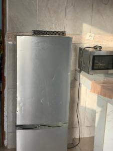 a refrigerator in a kitchen next to a microwave at Studio Salam in Ziguinchor