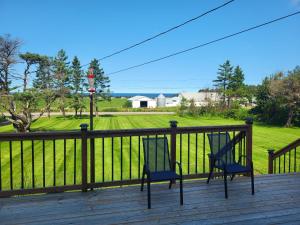 two chairs on a deck with a view of a field at Cavendish, 4 bedroom home in New Glasgow