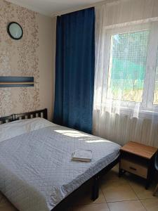 een slaapkamer met een bed en een raam met blauwe gordijnen bij Promenada in Węgierska Górka
