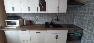 a kitchen with white cabinets and a sink and a microwave at Apartament Parkowa in Nowy Targ