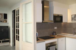 a kitchen with white cabinets and a sink and a tv at Blois La Tour 1696 in Blois