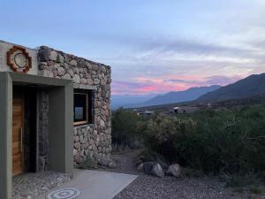 a stone building with a sunset in the background at Bendita Piedra Suites, Las Compuertas Lujan de Cuyo in Ciudad Lujan de Cuyo