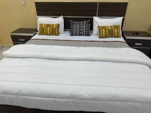 een groot wit bed met gele en zwarte kussens bij Hôtel bergmann in Ouro Sogui
