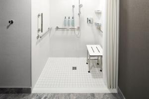 a white bathroom with a shower and a sink at Courtyard by Marriott Montreal Laval in Laval