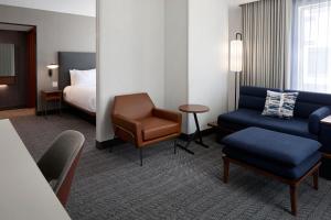 拉瓦尔Courtyard by Marriott Montreal Laval的一间配有床、沙发和椅子的酒店房间