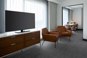 a hotel room with a flat screen tv and chairs at Courtyard by Marriott Montreal Laval in Laval
