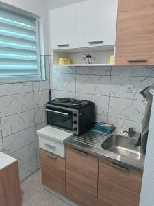 a kitchen with a sink and a microwave at Apartmani CENTAR in Jajce