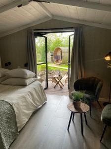 een slaapkamer met een bed en een stoel en een patio bij De Rode Zonnehoed in Scherpenzeel