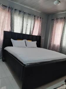 a large bed in a room with windows at The Alpha residence in Tema
