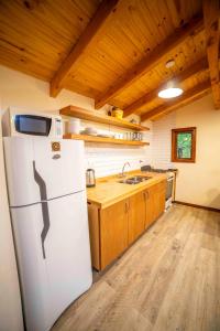 eine Küche mit einem weißen Kühlschrank und Holzschränken in der Unterkunft Casa en entorno de bosque, cerca de playas y cerros in San Carlos de Bariloche