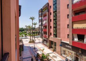 une vue sur une rue bordée de palmiers et de bâtiments dans l'établissement Appartement Chic Gueliz Plaza avec Vue, à Marrakech