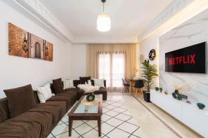 a living room with a couch and a tv at Appartement Chic Gueliz Plaza avec Vue in Marrakech