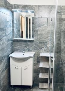 La salle de bains est pourvue d'un lavabo, d'un miroir et d'une douche. dans l'établissement H&A Suite Newly City Center 2 Bed & convenient, à Budapest