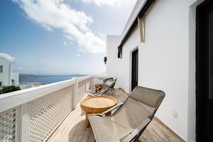 a balcony with two chairs and a wooden table at Aqua Luxury Suites Santorini in Imerovigli