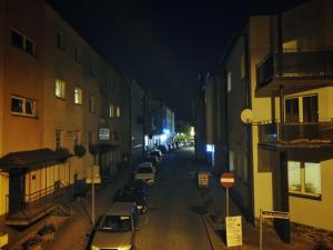 una calle de la ciudad por la noche con coches estacionados al lado de los edificios en Przystanek Sanok apartament w ścisłym centrum en Sanok
