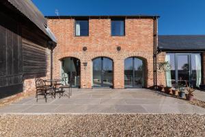 a brick building with a patio with a table and chairs at The Linhay in Peterborough