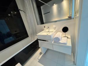 ein weißes Badezimmer mit einem Waschbecken und einem Spiegel in der Unterkunft Black&White Angel Apartment in Krakau