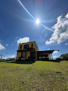 a house on a field with the sun in the sky at Rancho Luna in Cartago