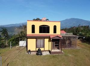 una pequeña casa amarilla sentada en la parte superior de un patio en Rancho Luna, en Cartago