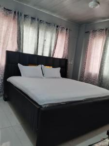 a large bed in a room with windows at The Alpha* residence in Tema