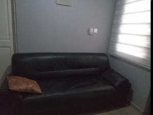 a black leather couch sitting in a living room at The Alpha* residence in Tema