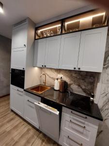 a kitchen with white cabinets and a sink at Apartament Kluskowe Widoki in Kluszkowce