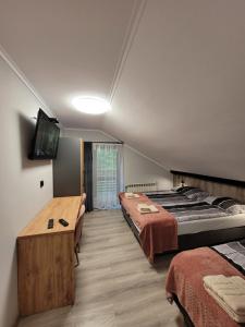 a bedroom with two beds and a flat screen tv at Zajazd Wernyhora in Sułoszowa