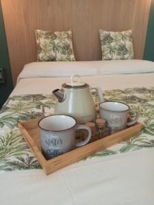 a tray with two cups and a tea kettle on a bed at Intrecci & Impasti in Naples