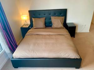 - un lit avec une tête de lit bleue dans l'établissement Appartement spacieux, à Drancy