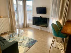 un salon avec un canapé, une table et une télévision dans l'établissement Appartement spacieux, à Drancy