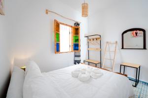 Un dormitorio con una cama blanca con toallas. en Giraffe Hostel-Sea view Rooftop en Esauira