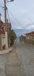 an empty street with buildings and the ocean in the background at Perle in Aïn El Turk