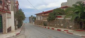 an empty street next to a stone wall at Perle in Aïn El Turk