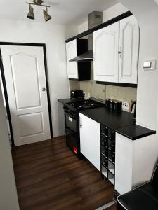 a kitchen with white cabinets and a black counter top at Kensington Stories - 4 Bed House in Watford